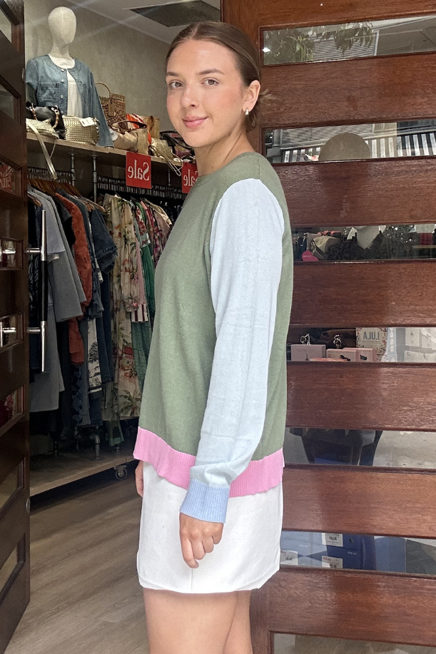 Woman standing in front of a store entrance with clothing racks inside