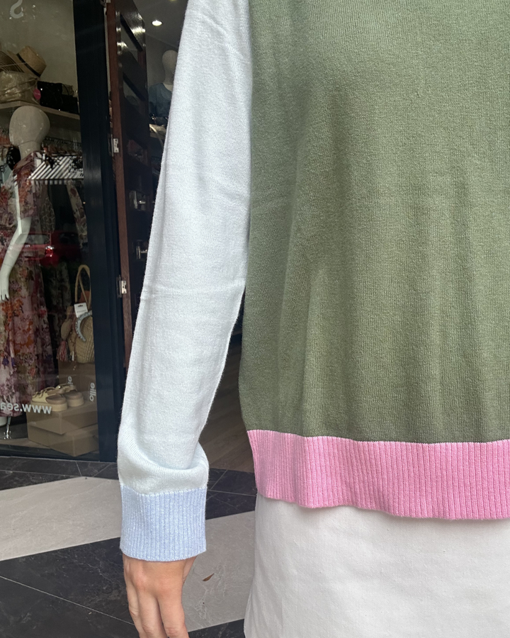 Green sweater with pink hem and light blue sleeves in a store setting