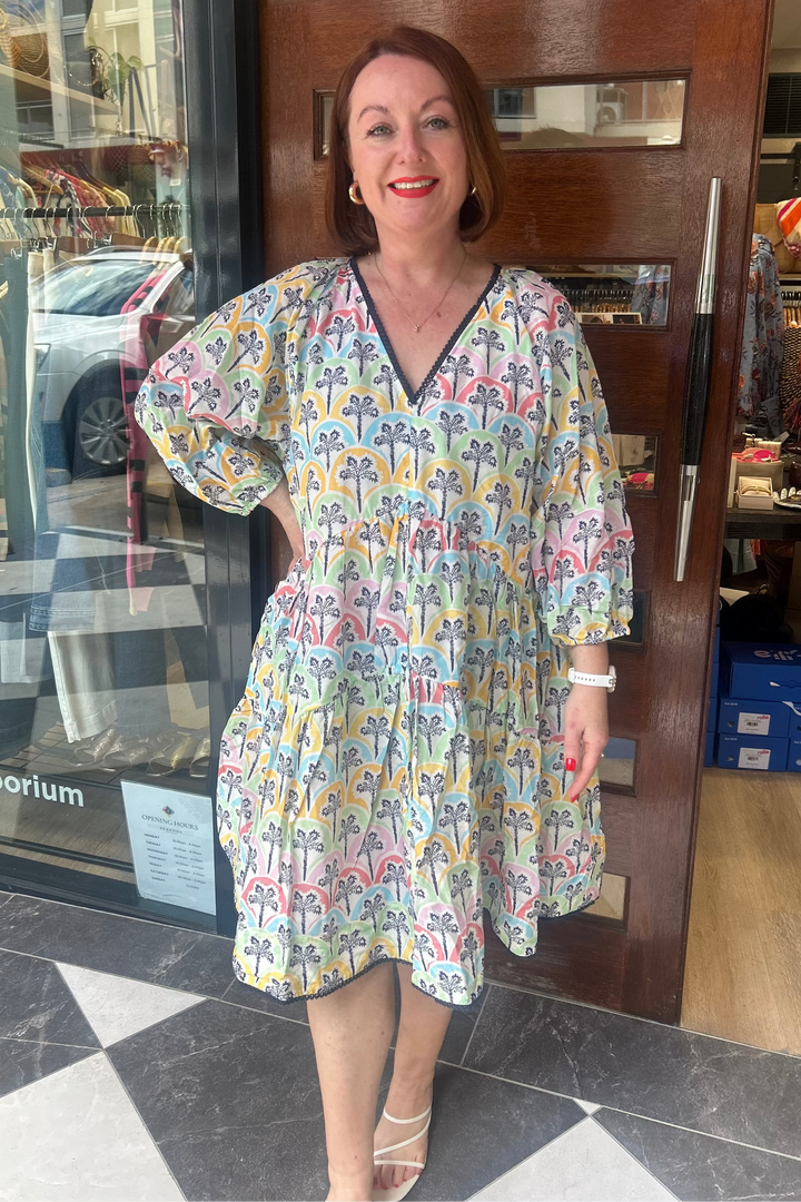 Woman in a colorful dress standing in front of a store entrance.