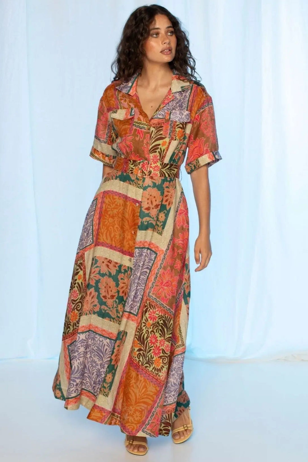 Woman wearing a colorful patchwork dress against a white background