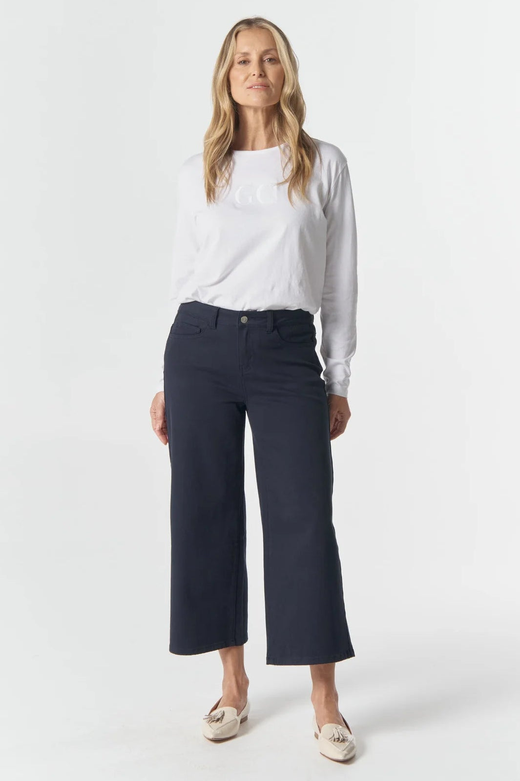 Woman wearing a white shirt and navy pants on a white background