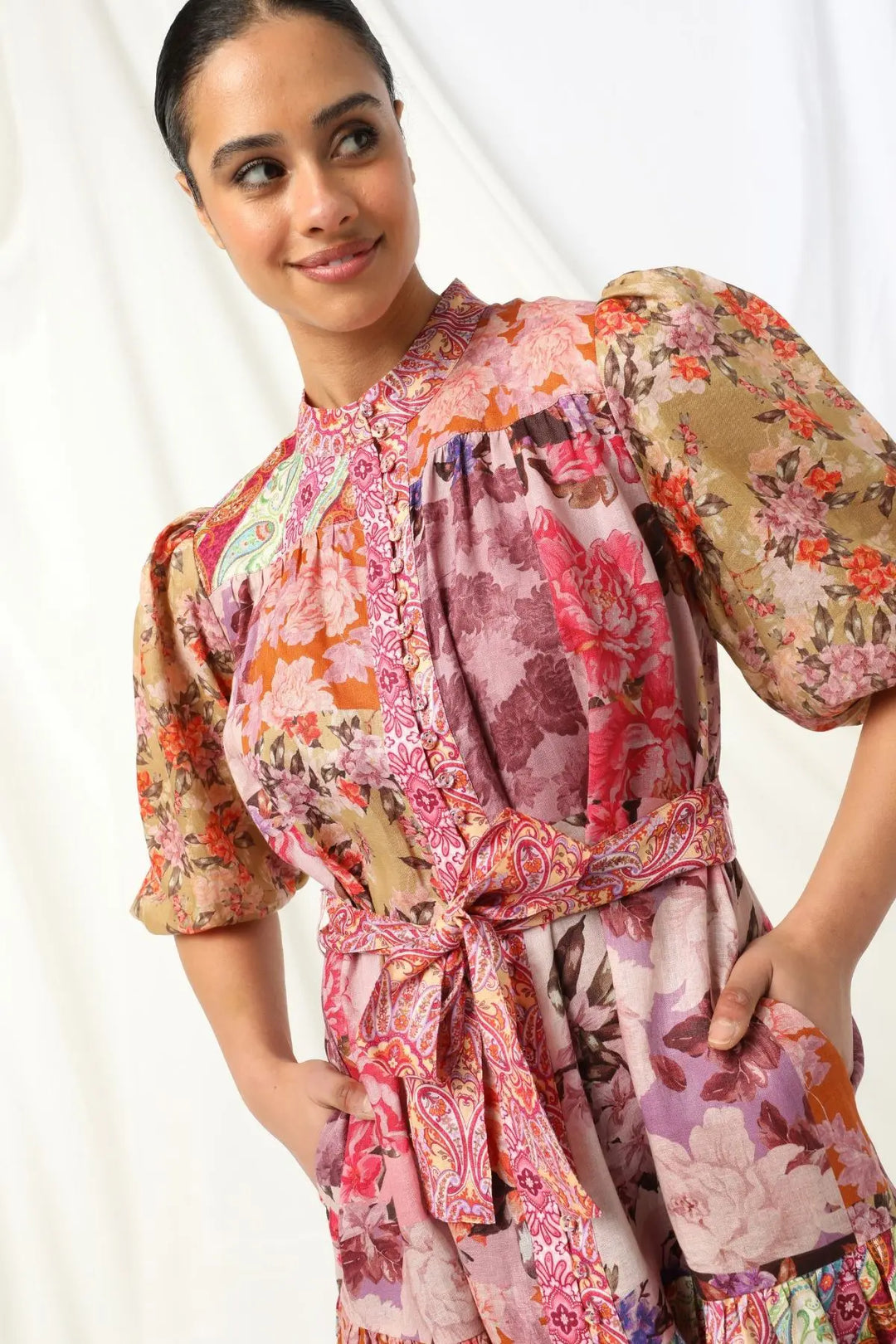 Woman wearing a colorful floral dress against a white background