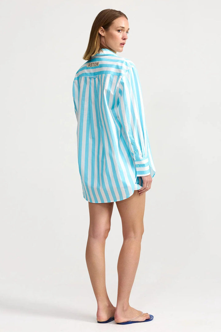 Woman wearing a blue and white striped shirt on a white background. Aston Studio Buddy Shirt Caribbean Stripe
