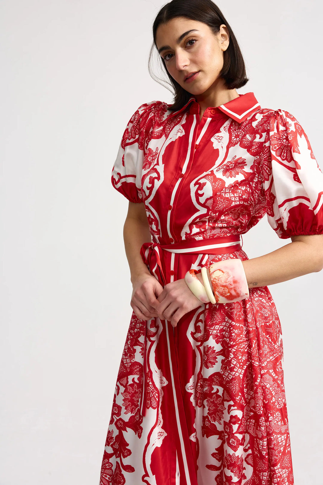 Woman wearing a red and white patterned dress on a plain background