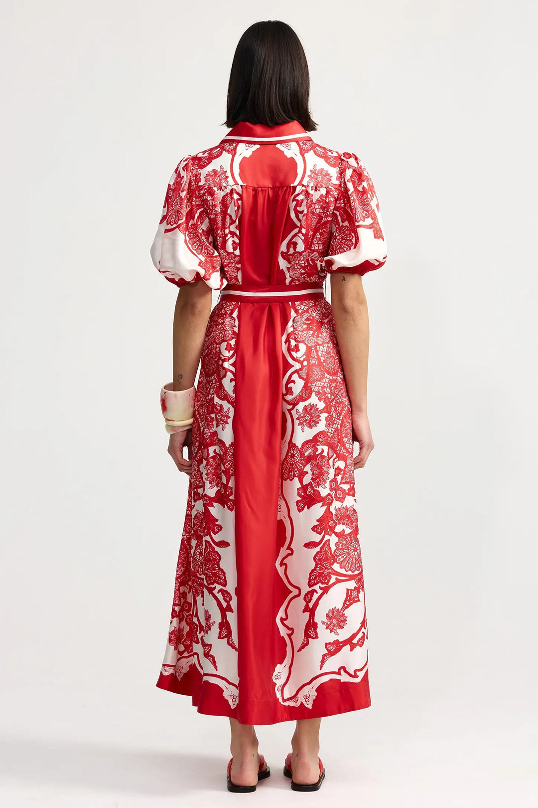 Woman wearing a red and white floral dress on a white background
