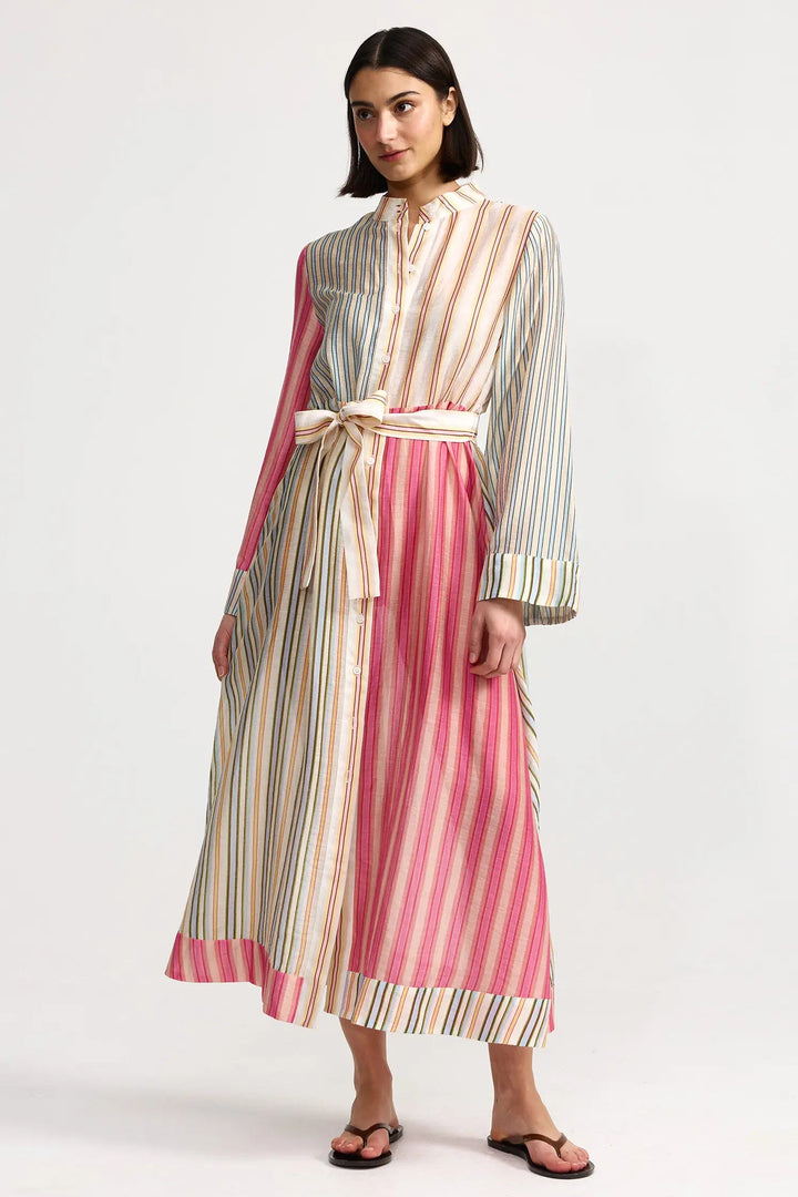 Woman wearing a long, striped dress with a belt on a white background. Aston Studio Neotta Dress Peony Multi Stripe