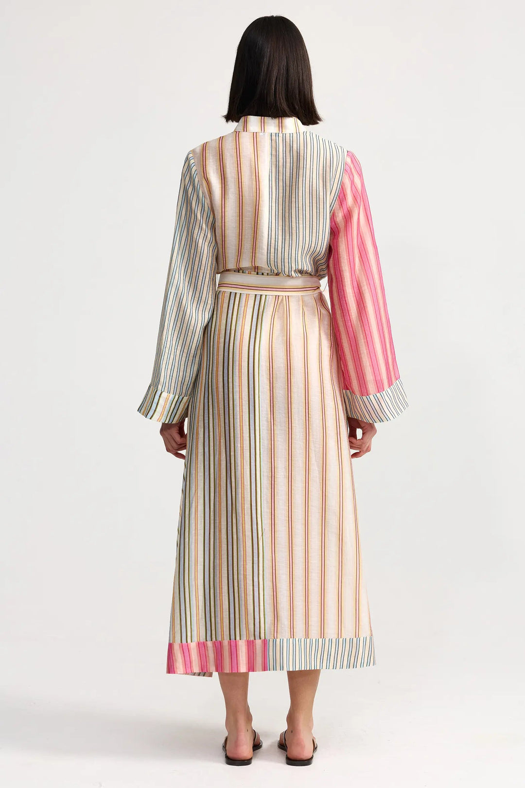 Woman wearing a long, multicolored striped dress on a white background. Aston Studio Neotta Dress Peony Multi Stripe