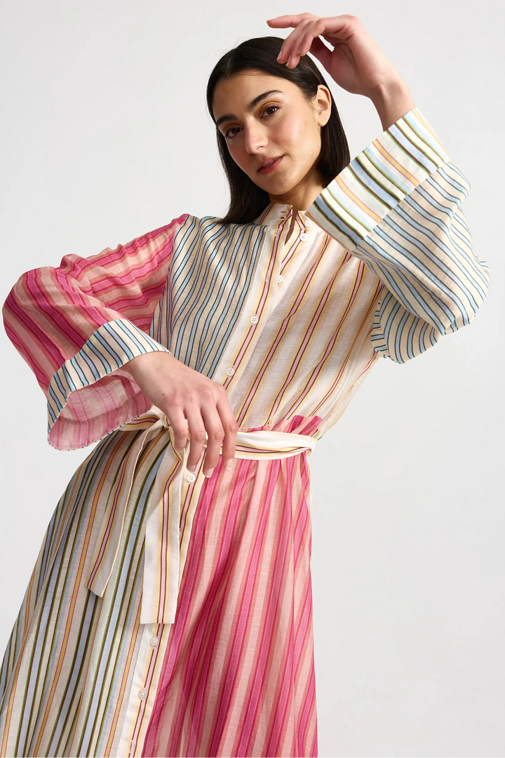 Woman wearing a colorful striped dress on a white background. Aston Studio Neotta Dress Peony Multi Stripe