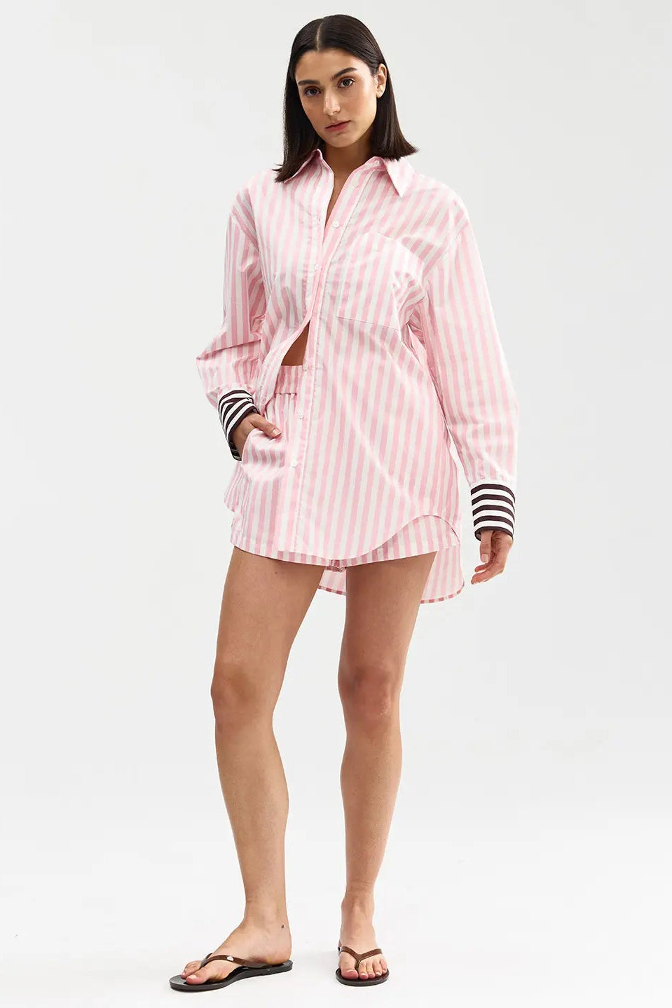Woman wearing a pink striped shirt and shorts on a white background