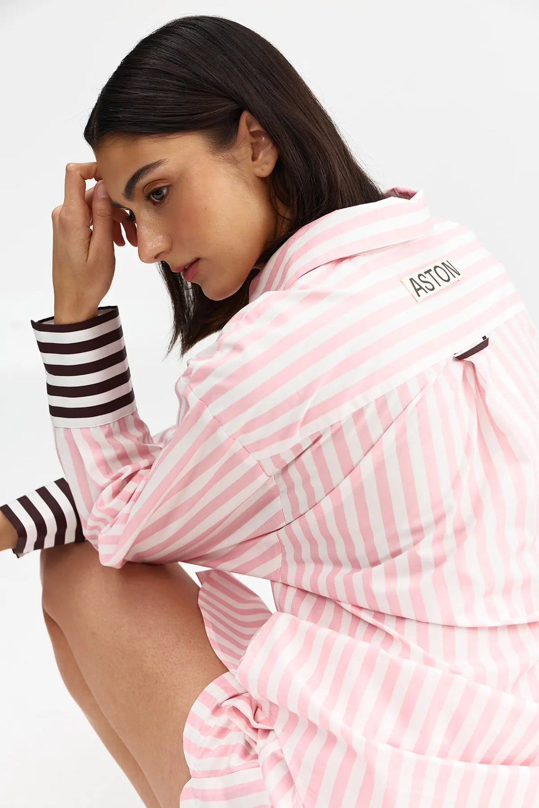 Woman wearing a pink and white striped outfit with 'ASTON' branding on a white background
