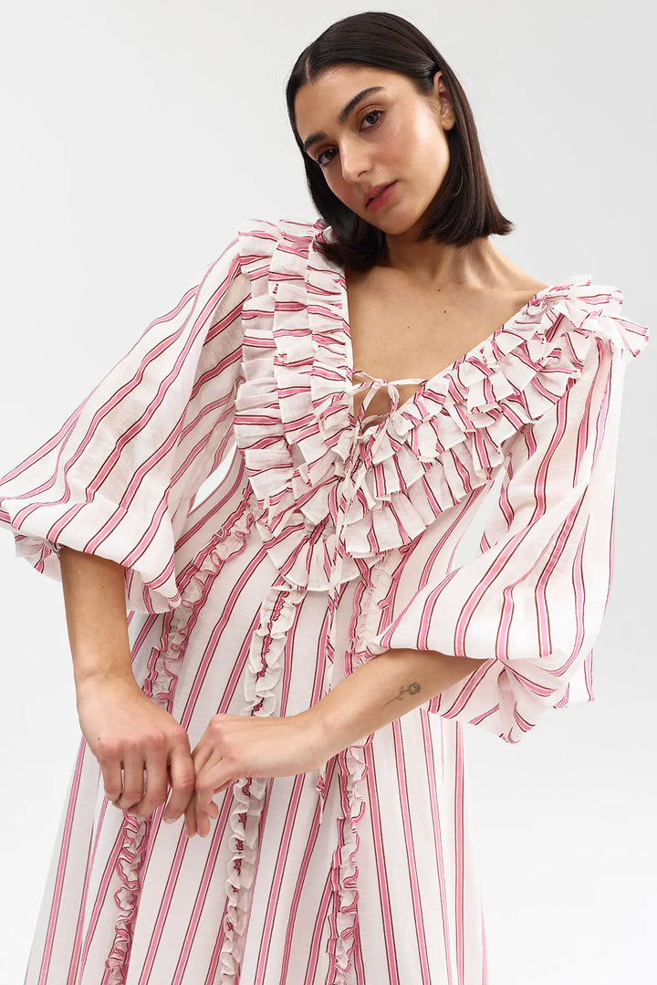 Woman wearing a pink and white striped dress with ruffled sleeves on a white background