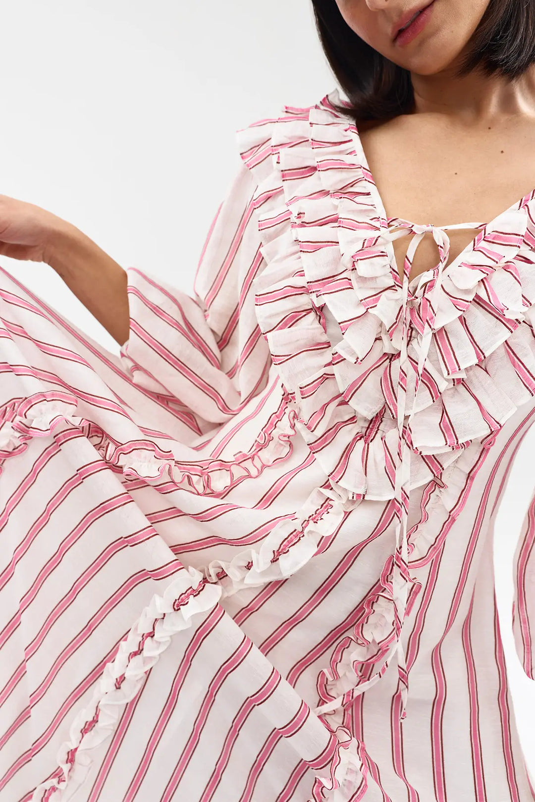 Woman wearing a pink and white striped dress with ruffled details.