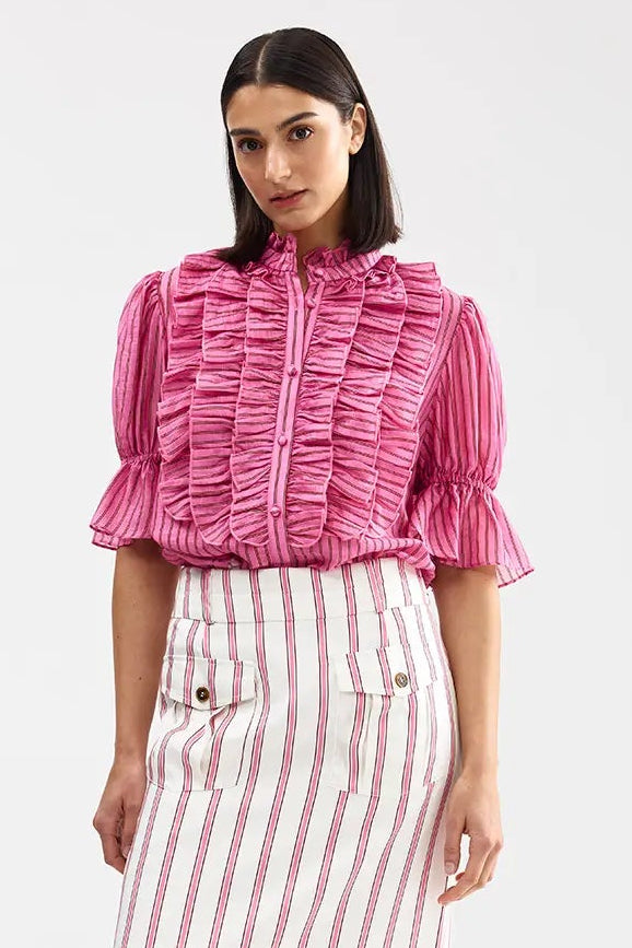 Woman wearing a pink ruffled blouse and red and white striped skirt on a white background