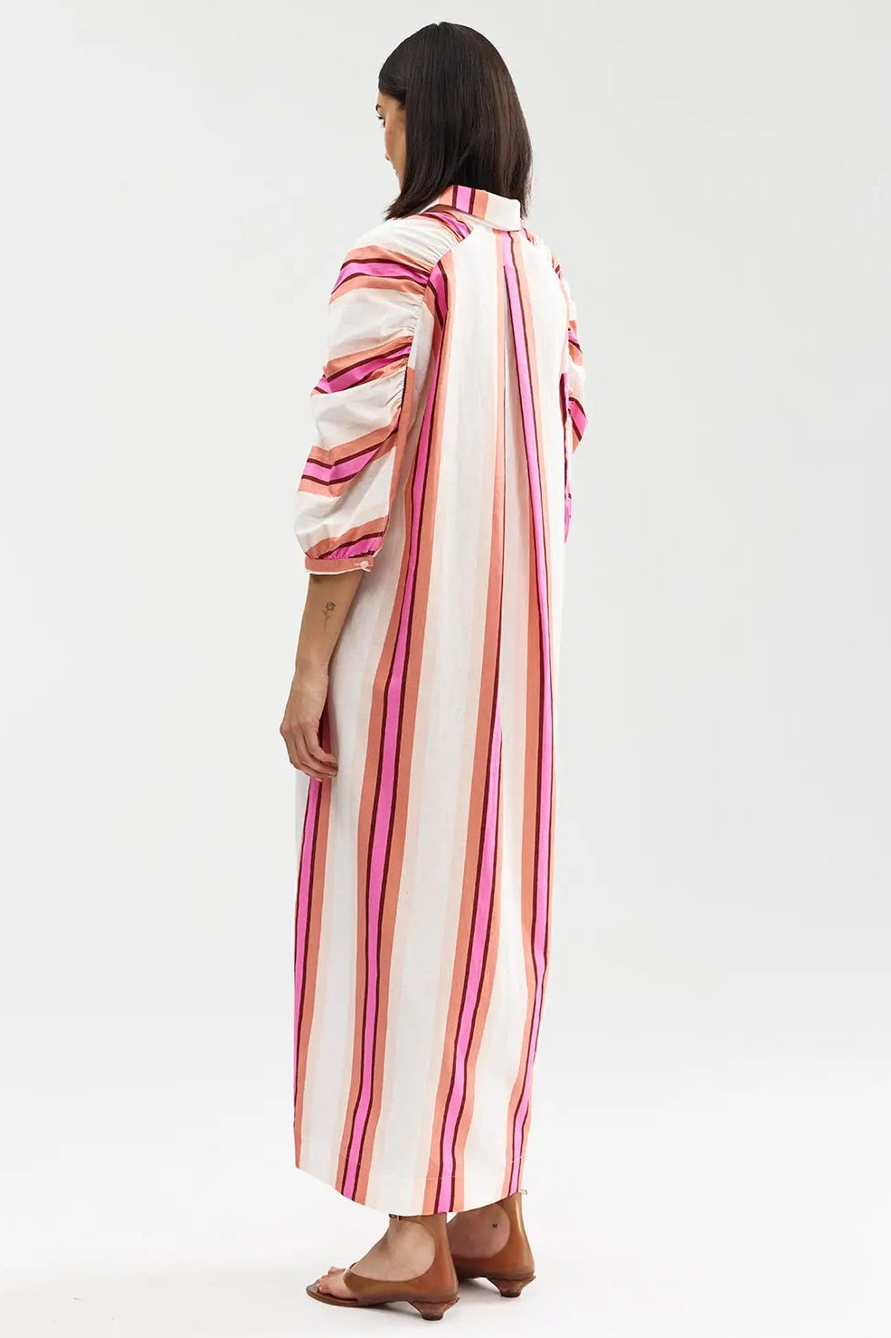 Woman wearing a long, striped dress on a white background