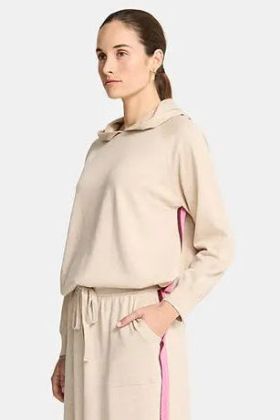 Woman wearing a beige outfit with pink accents on a white background