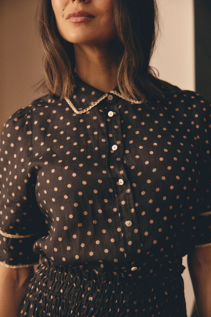 Woman wearing a black polka dot blouse against a neutral background