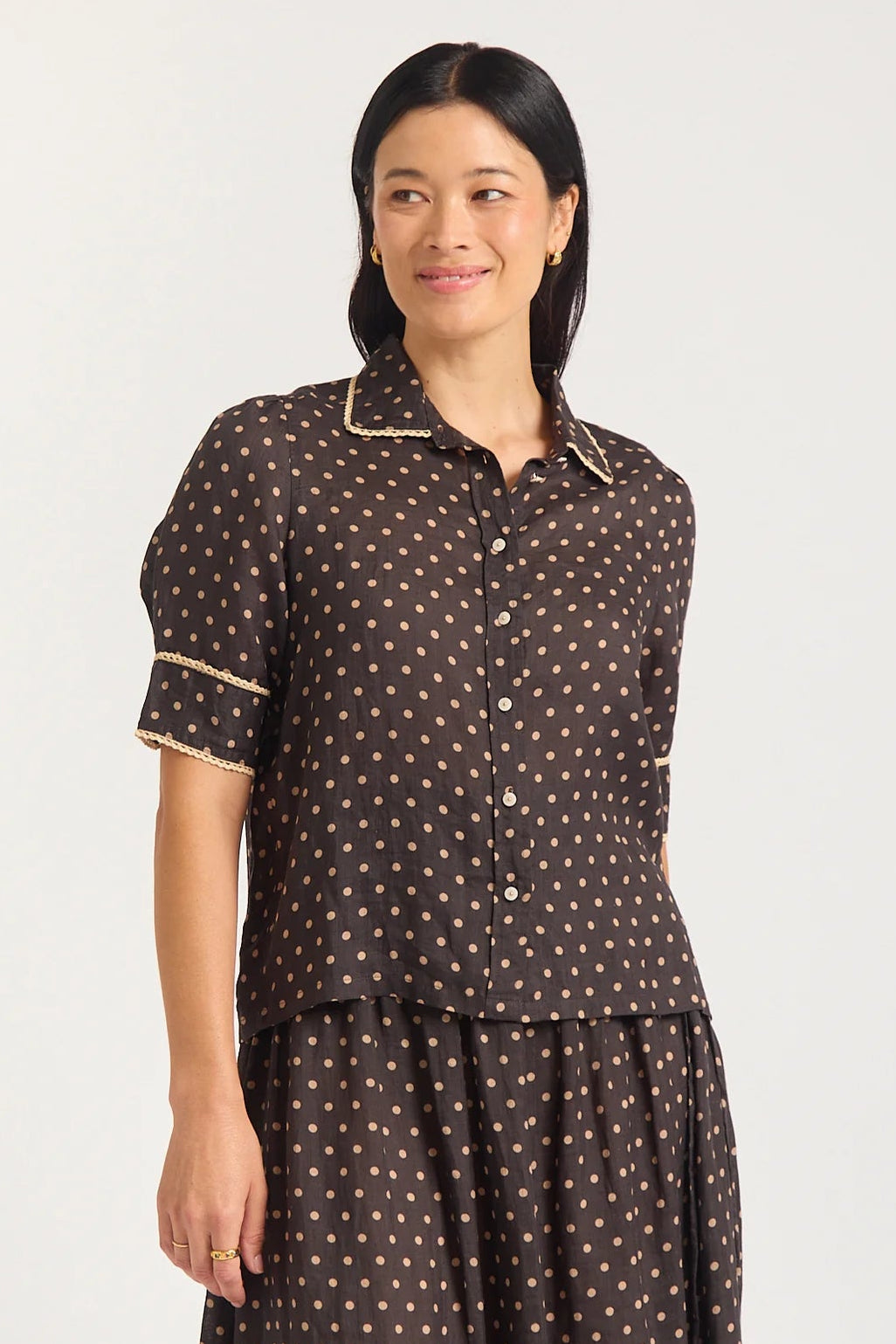 Woman wearing a brown polka dot dress with a white background