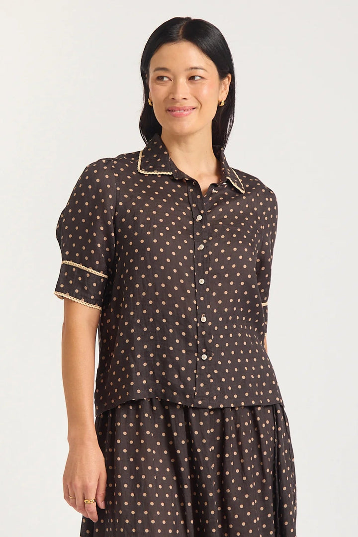 Woman wearing a brown polka dot dress with a white background