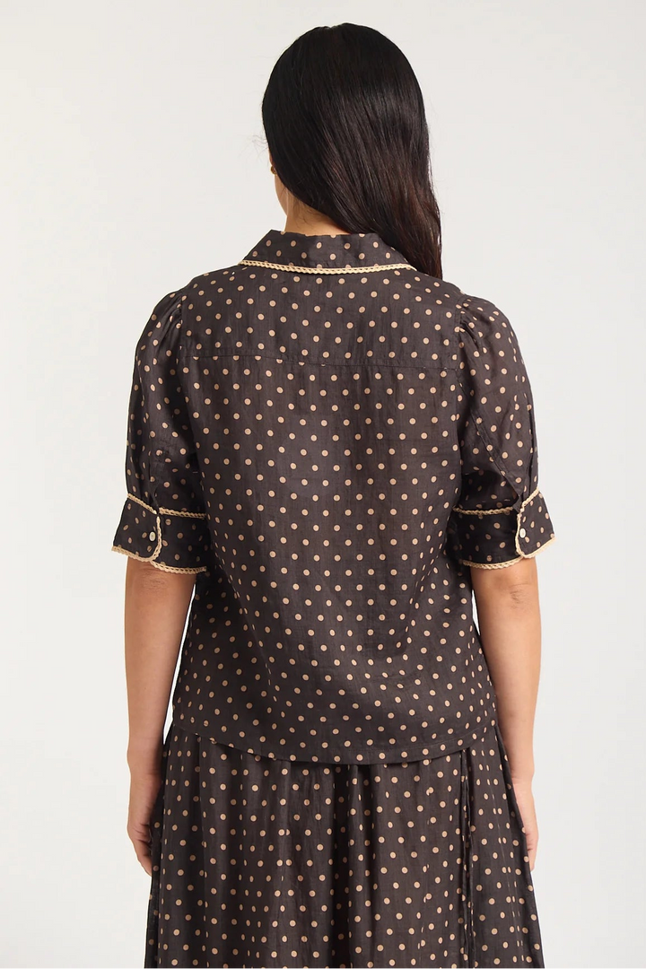 Woman wearing a brown dress with gold polka dots on a white background