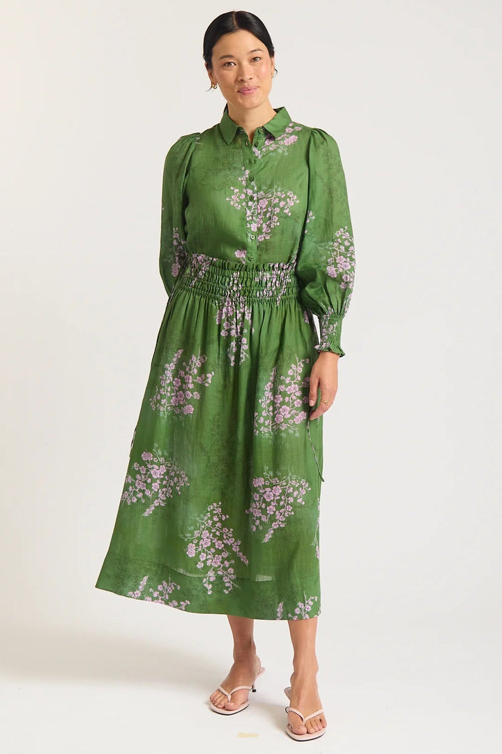 Woman wearing a green floral dress against a white background