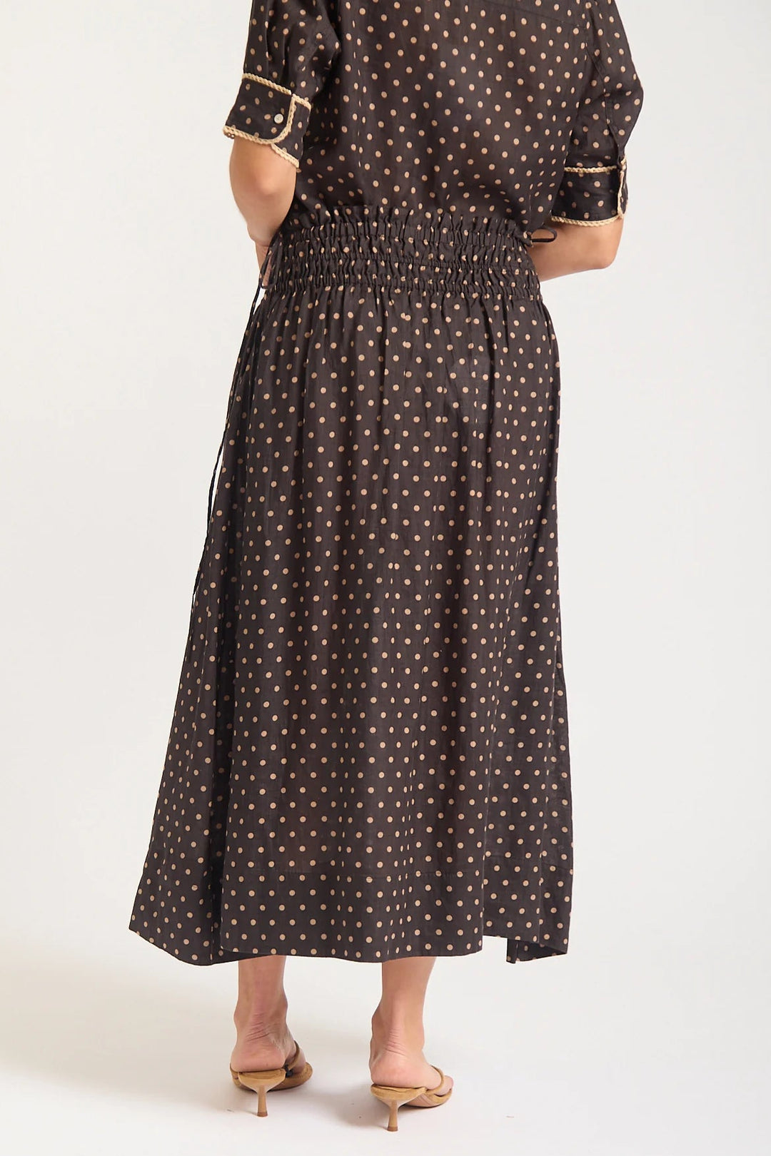 Person wearing a brown polka dot dress on a white background
