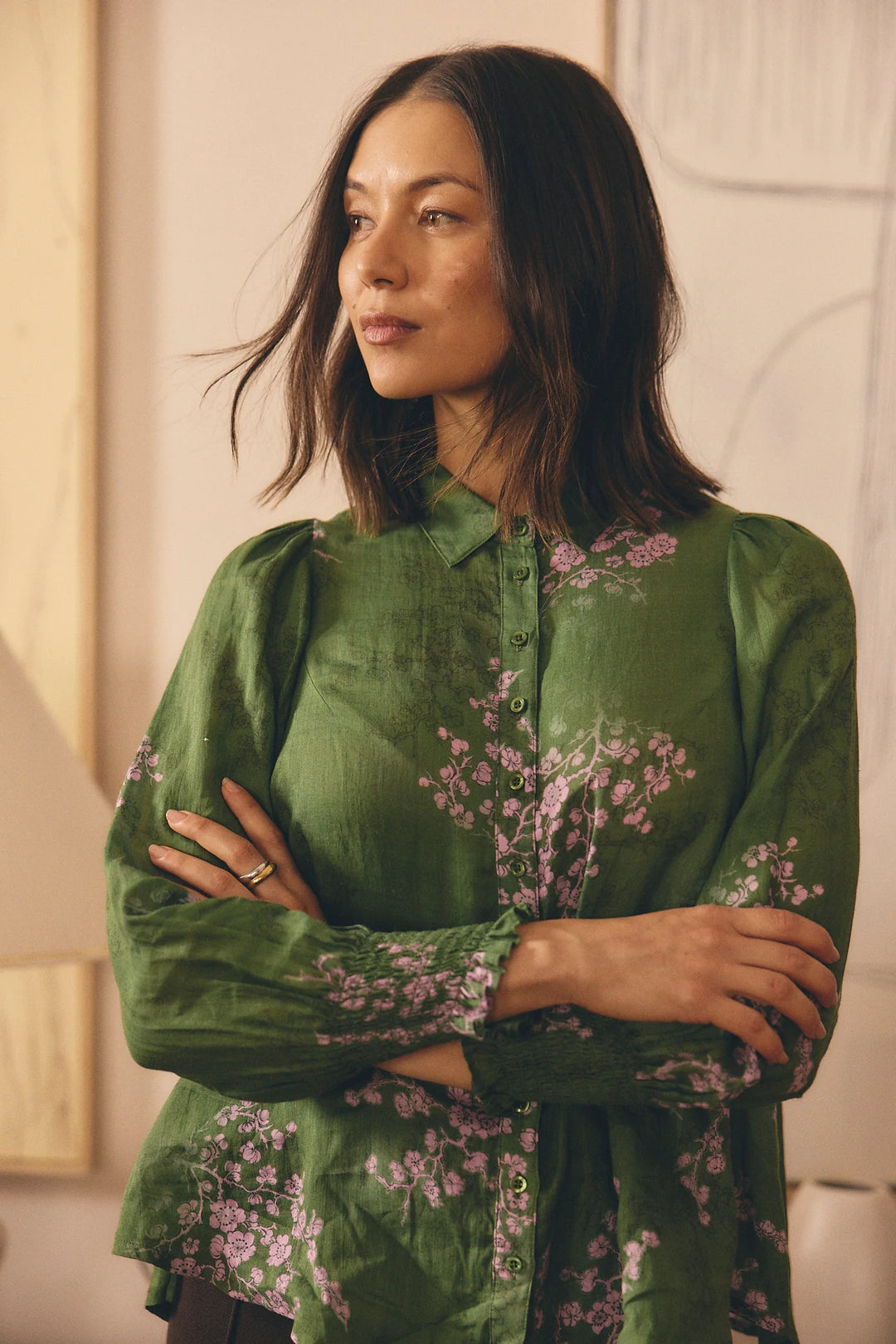 Woman wearing a green floral blouse with a neutral background