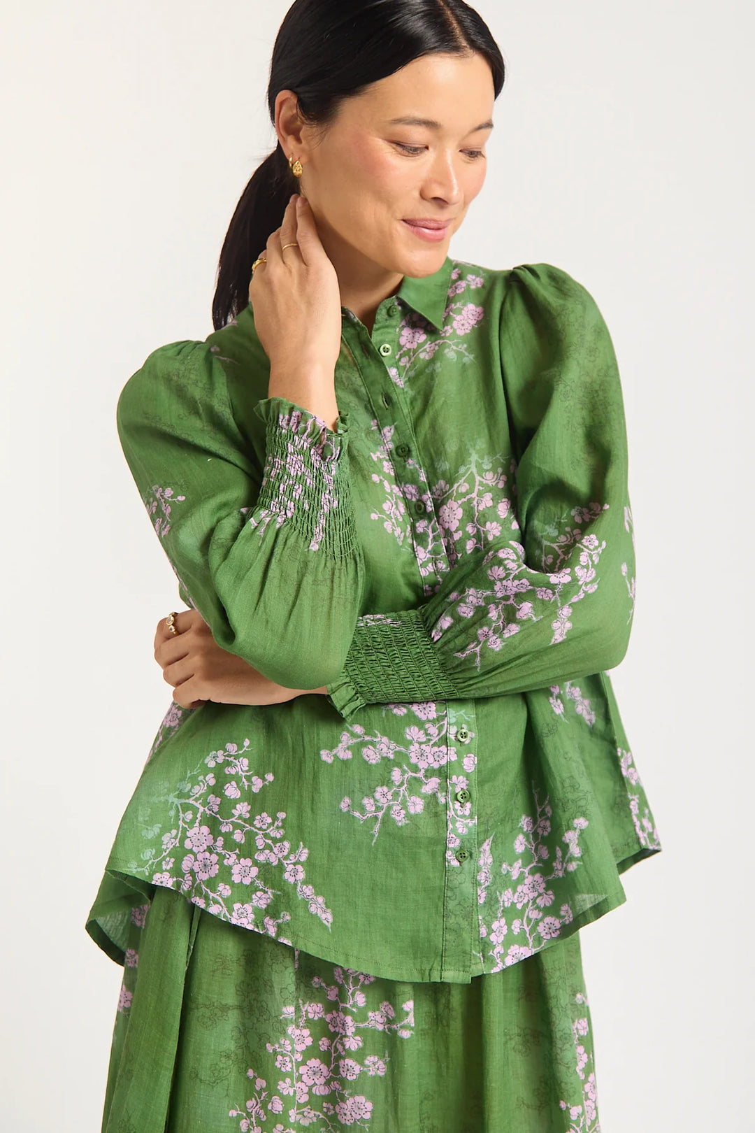 Woman wearing a green floral blouse and skirt on a white background