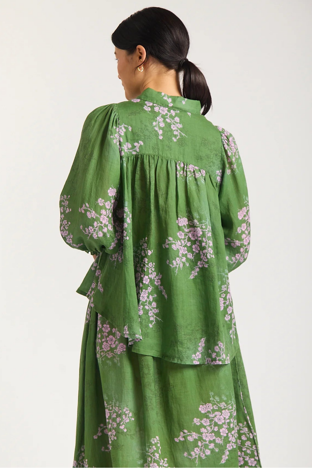 Woman wearing a green floral dress against a white background