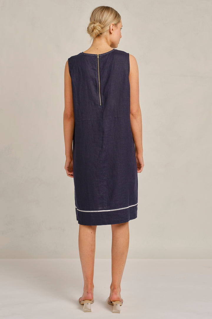 Woman wearing a navy sleeveless dress against a plain background