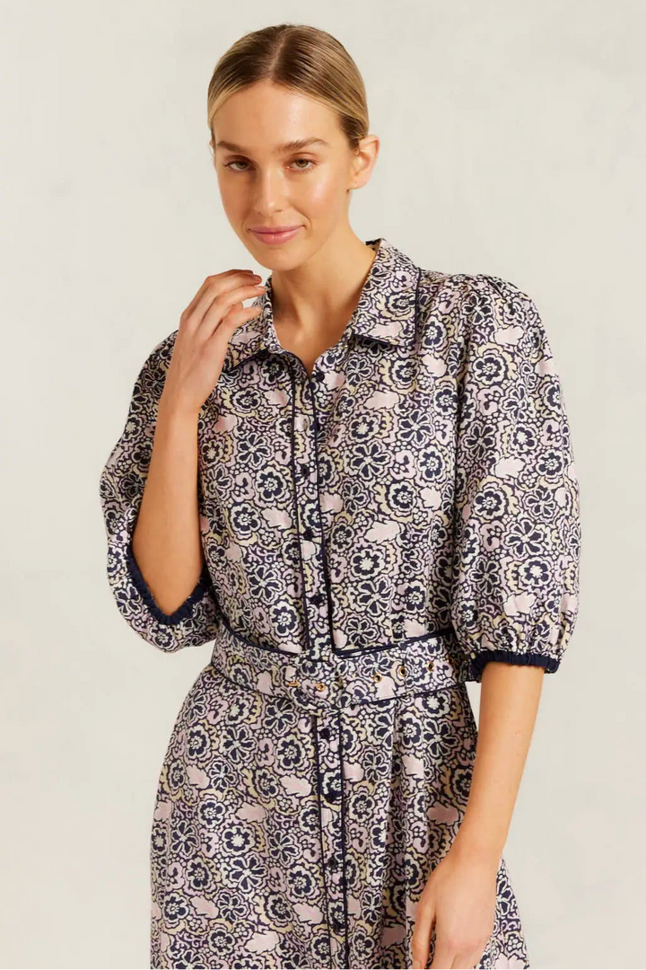 Woman wearing a patterned dress against a plain background
