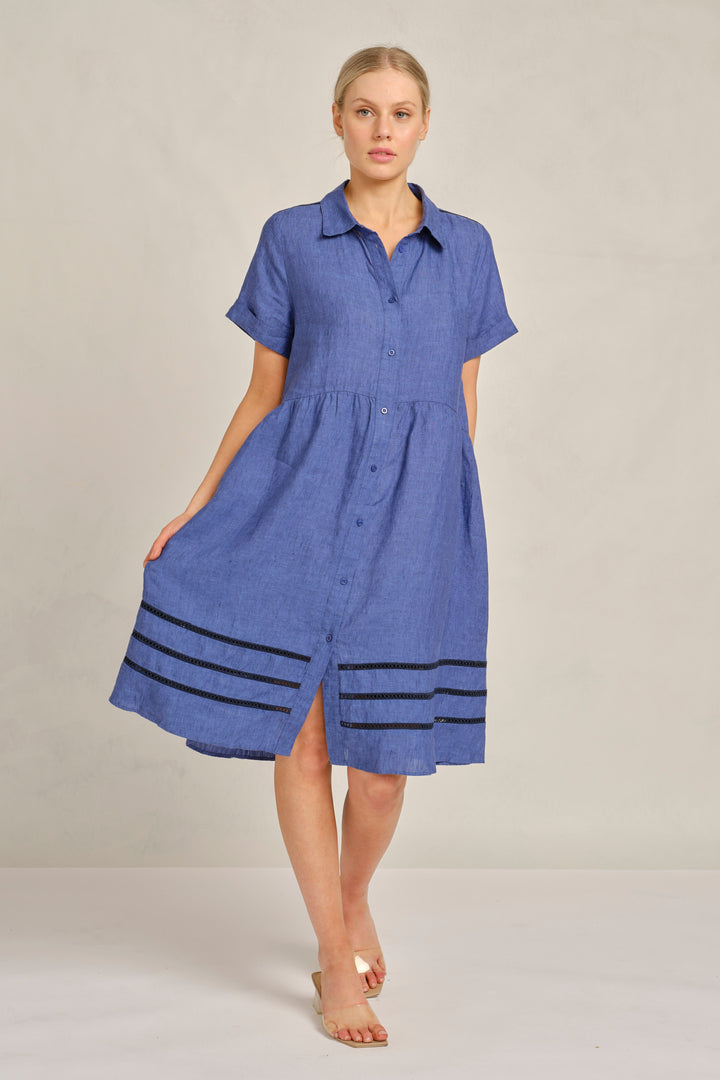 Woman wearing a blue dress with black stripes on a plain background