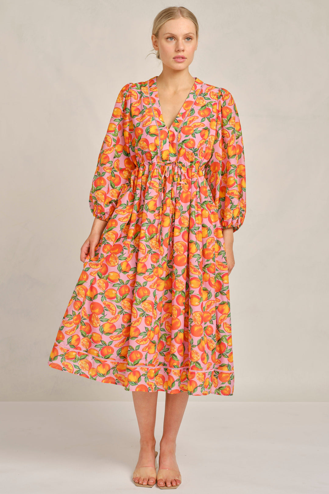 Woman wearing a colorful floral dress on a plain background