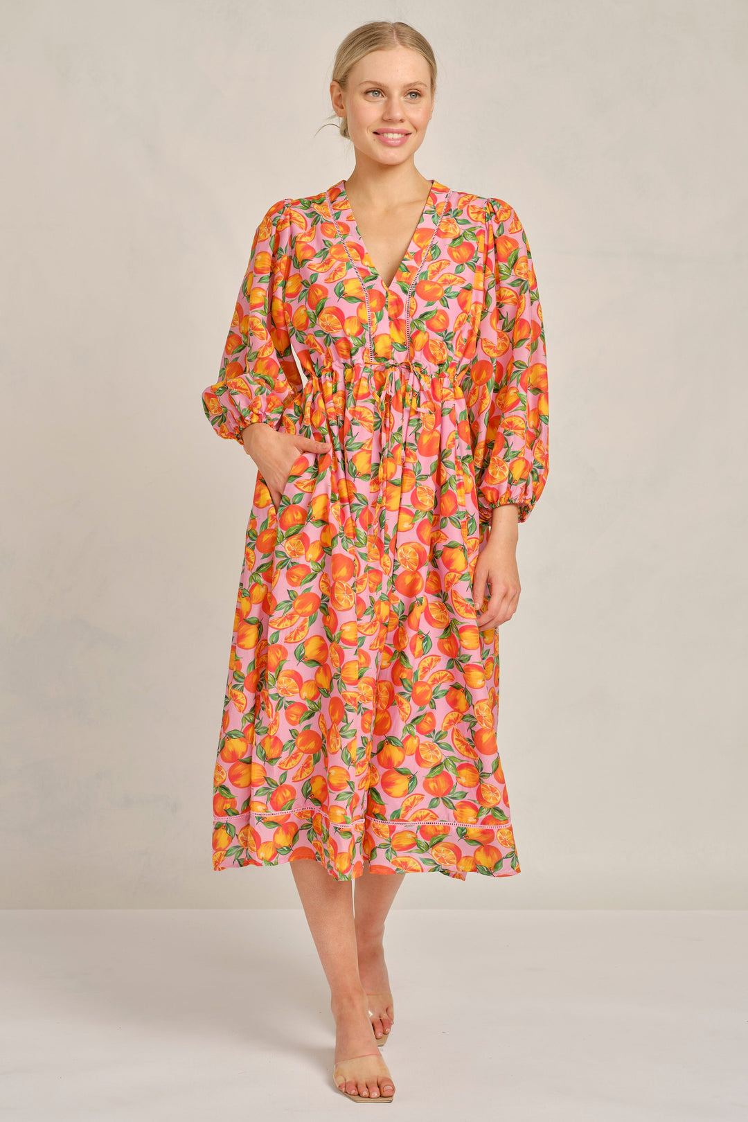 Woman wearing a colorful floral dress on a plain background