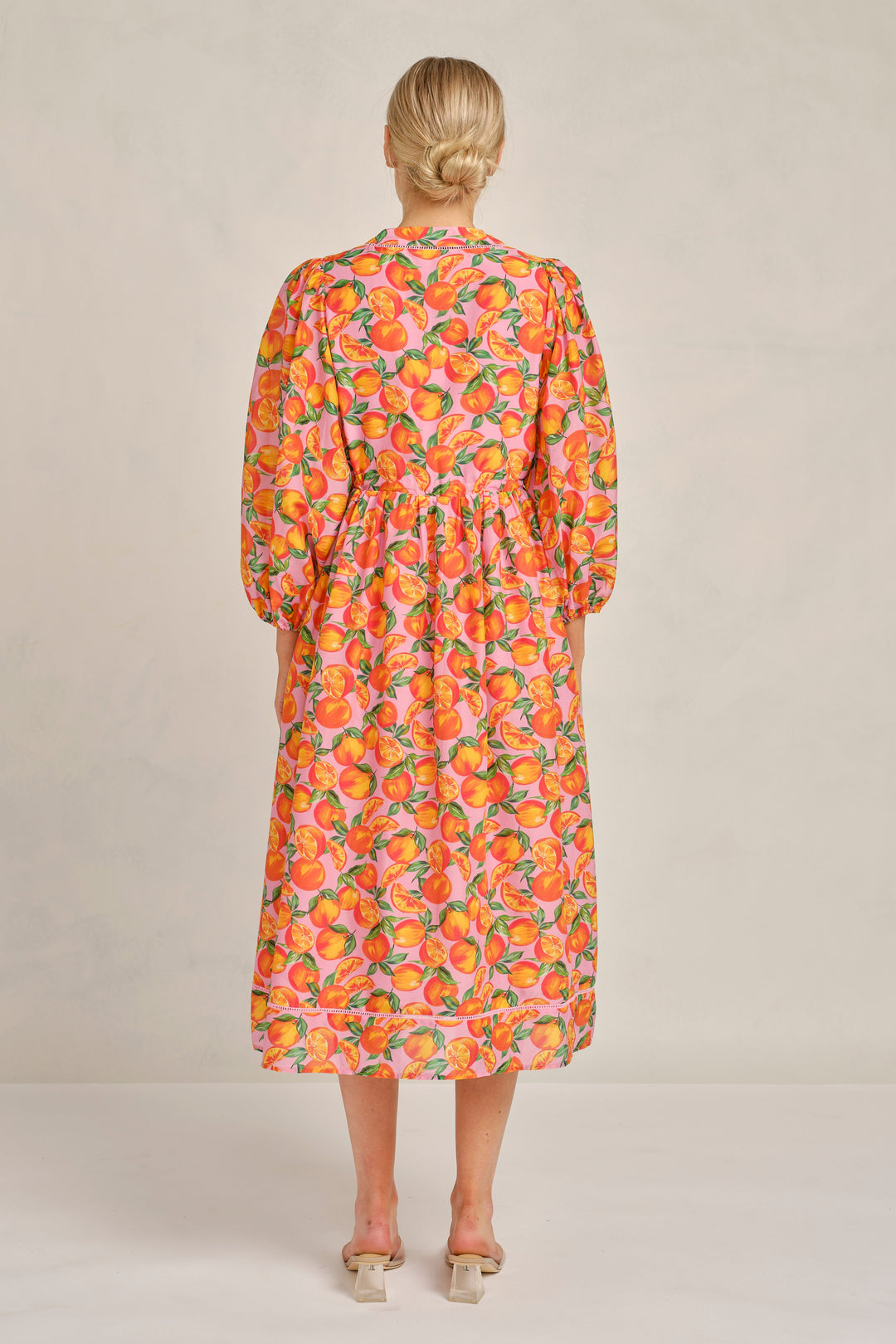 Woman wearing a floral dress with long sleeves on a plain background