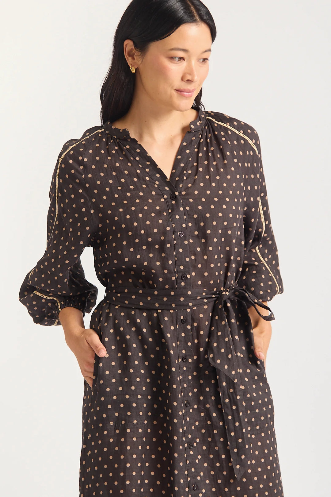 Woman wearing a black dress with gold polka dots on a white background