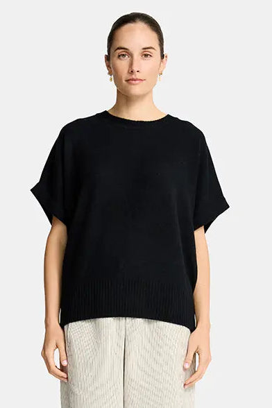 Woman wearing a black top and beige pants on a white background