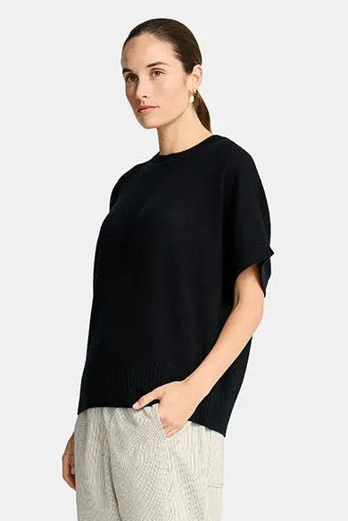 Woman wearing a black top and beige pants on a white background