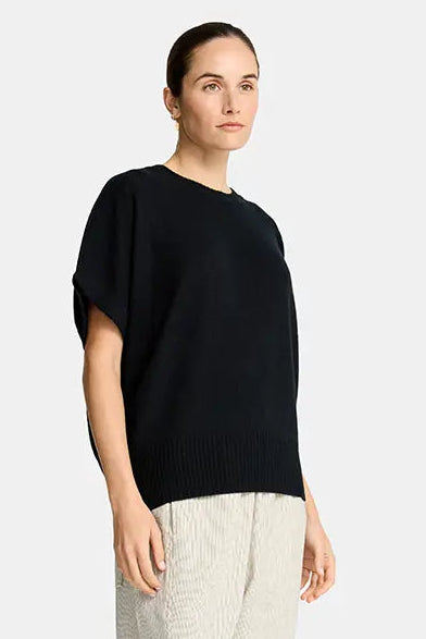 Woman wearing a black top and beige pants on a white background