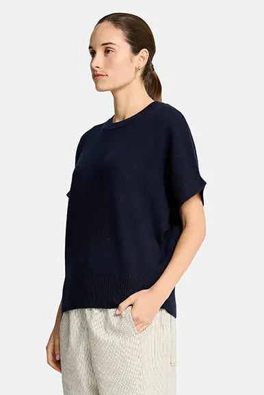 Woman wearing a navy top and beige pants on a white background