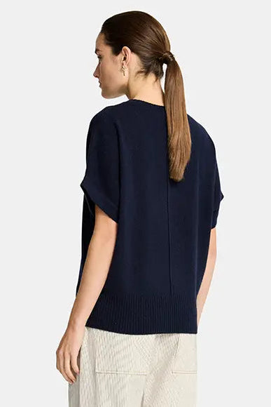 Woman wearing a navy blue top and beige pants on a white background