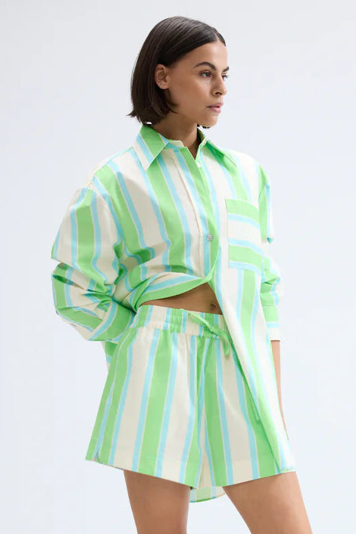 Woman wearing a green and white striped outfit on a white background. Aston Studio Buddy Shirt Fern Lapis Stripe 