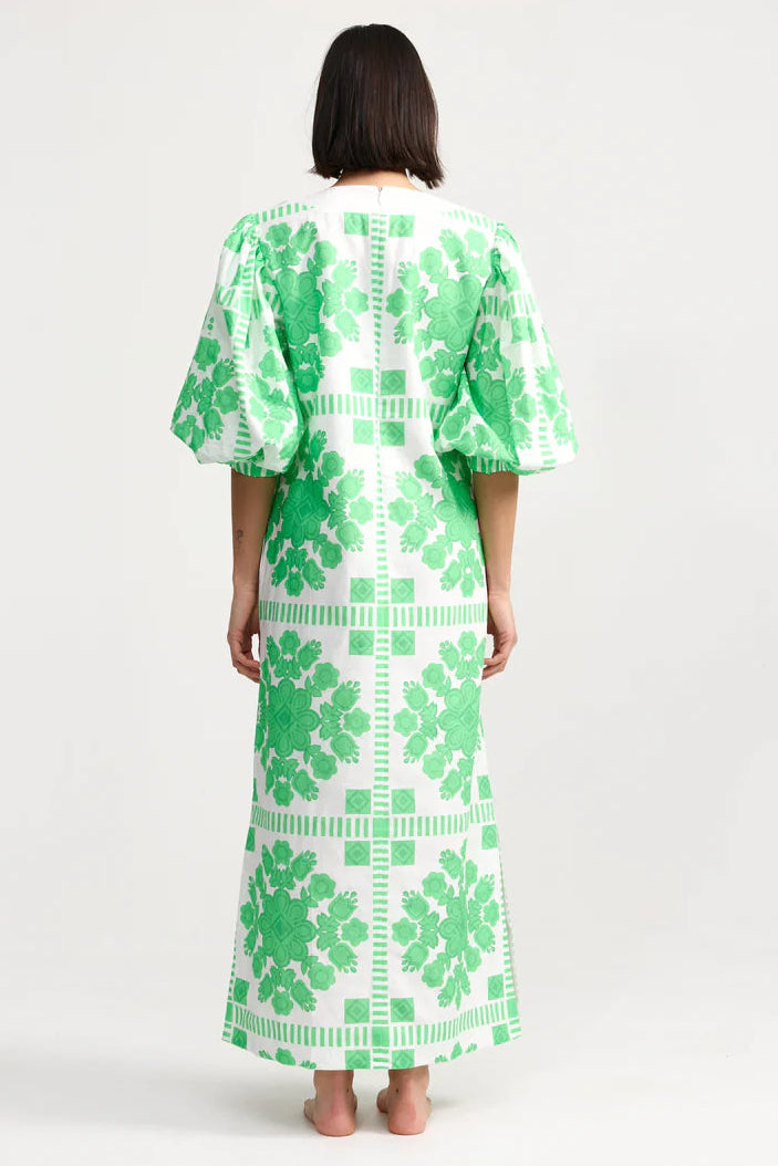 Person wearing a green and white patterned dress on a white background. Aston Studio Doris Dress Mediterranean Fern