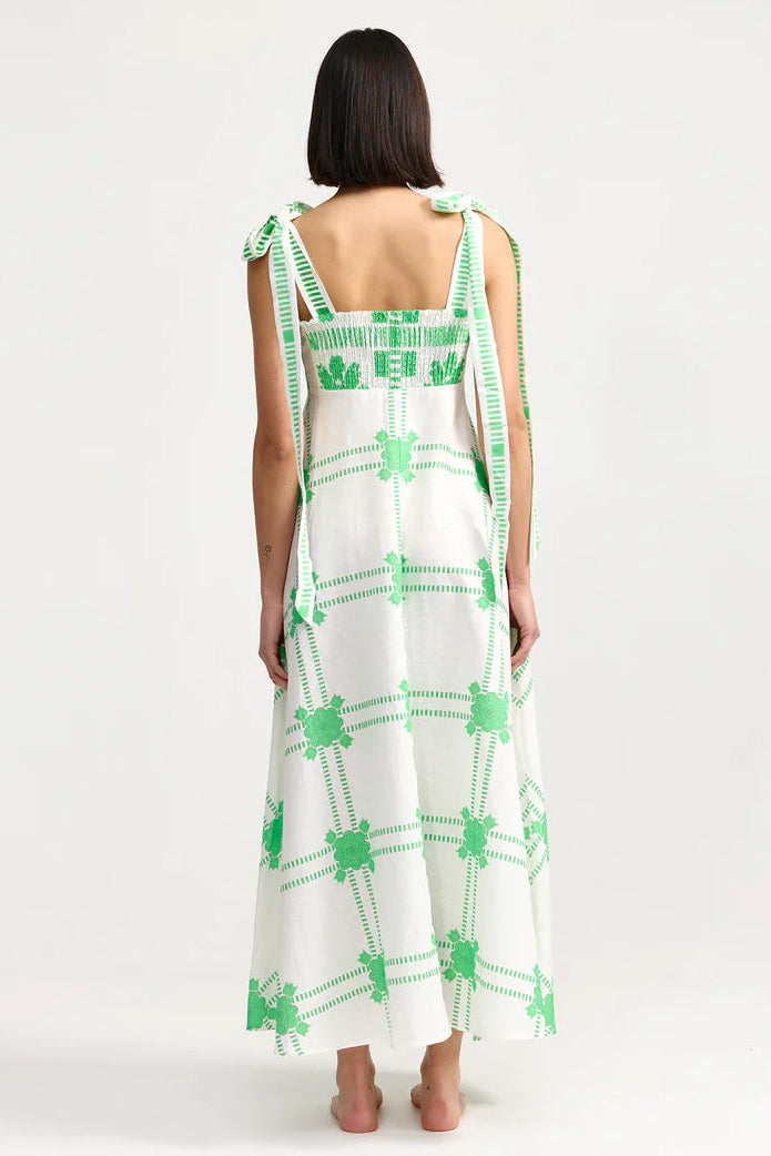 Woman wearing a white dress with green patterns on a white background. Aston Studio Pippa Dress Mediterranean Fern