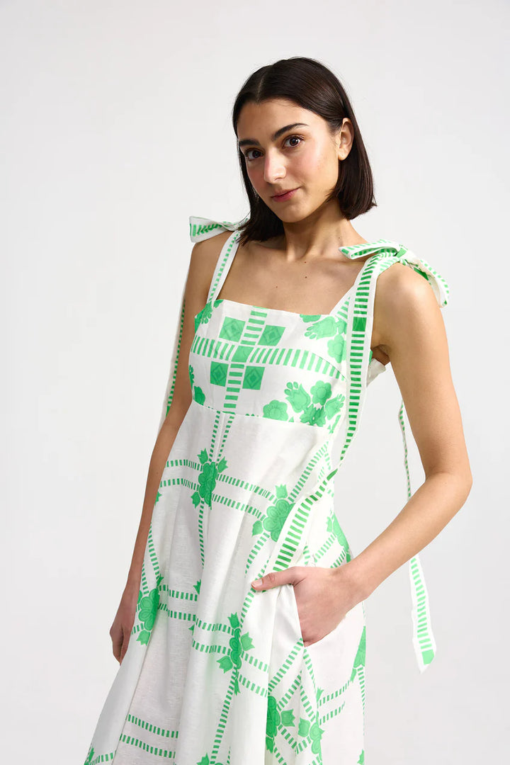 Woman wearing a white dress with green patterns on a white background. Aston Studio Pippa Dress Mediterranean Fern