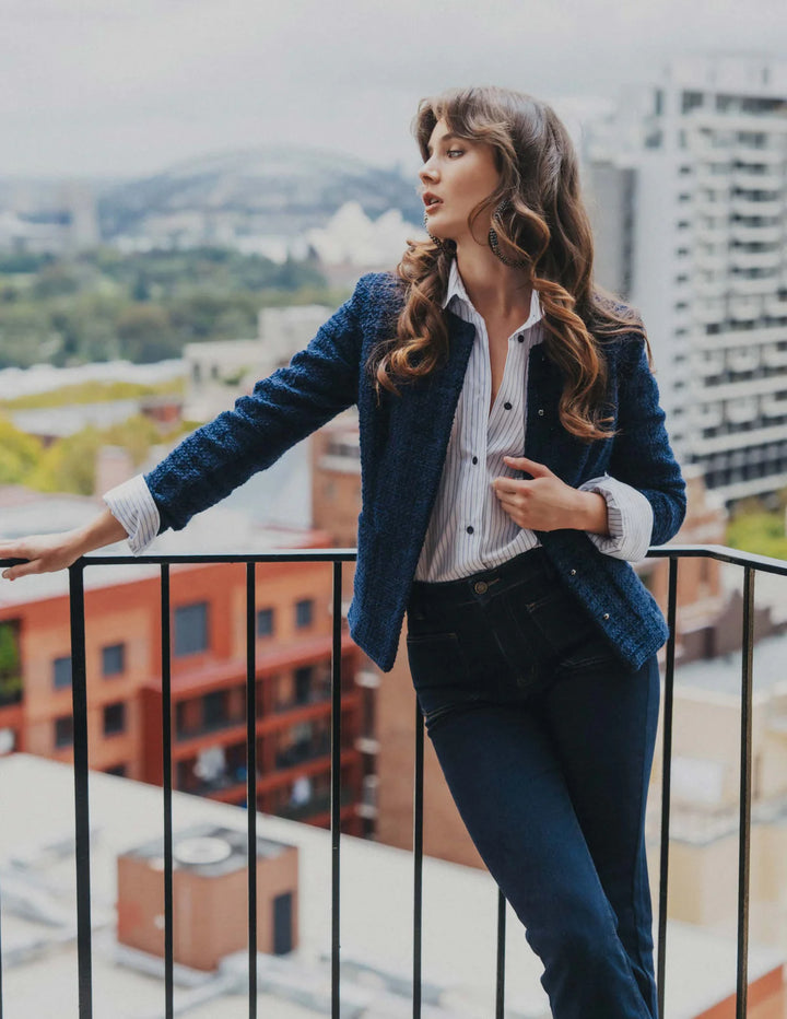 Woman standing on a balcony with a cityscape in the background