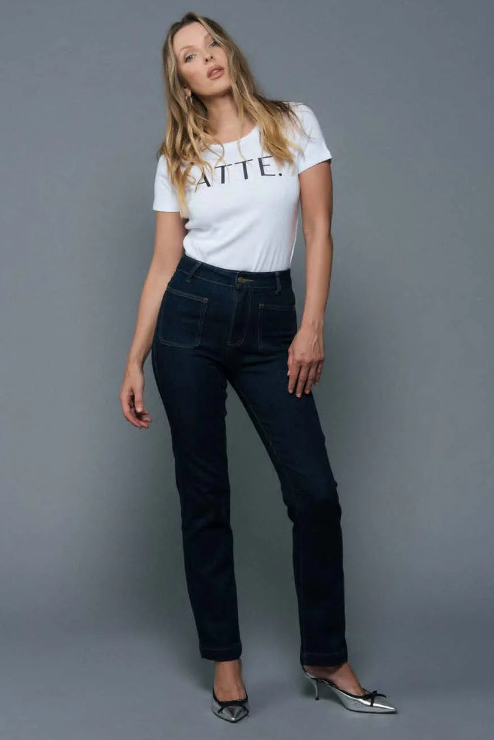 Woman wearing a white t-shirt with text and dark jeans against a gray background