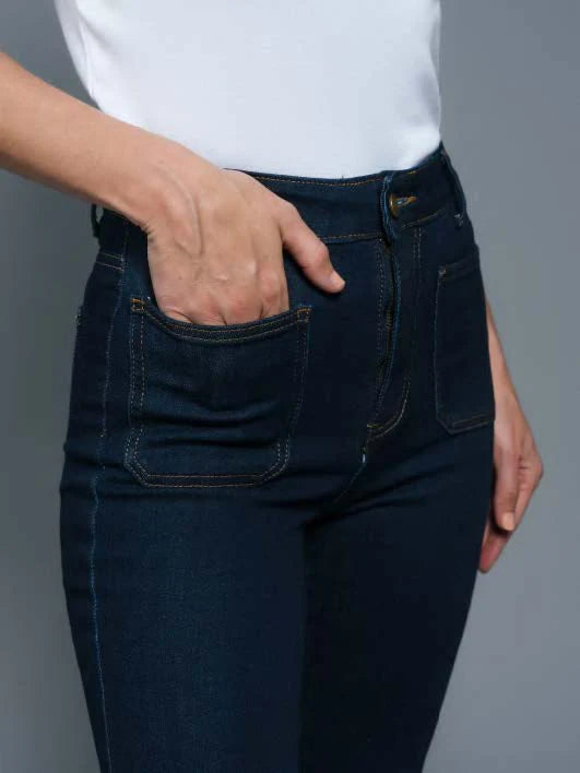 Person wearing dark blue jeans with a plain background