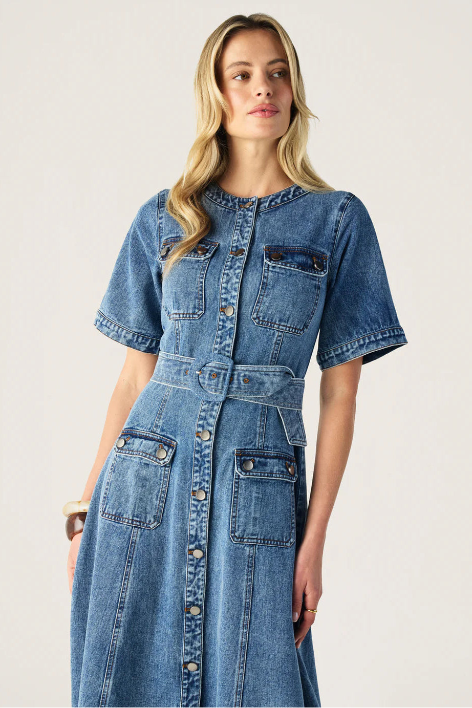 Woman wearing a denim dress against a plain background