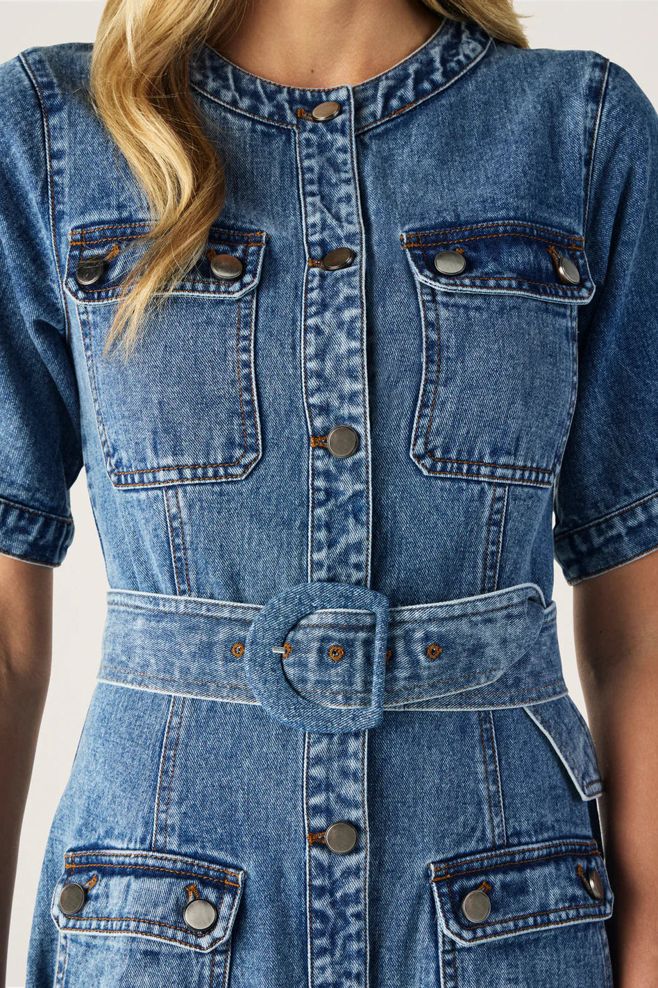 Close-up of a blue denim dress with a belt on a plain background