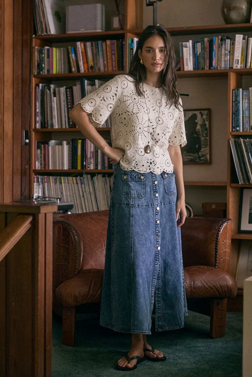 Woman standing in a room with bookshelves and a leather chair